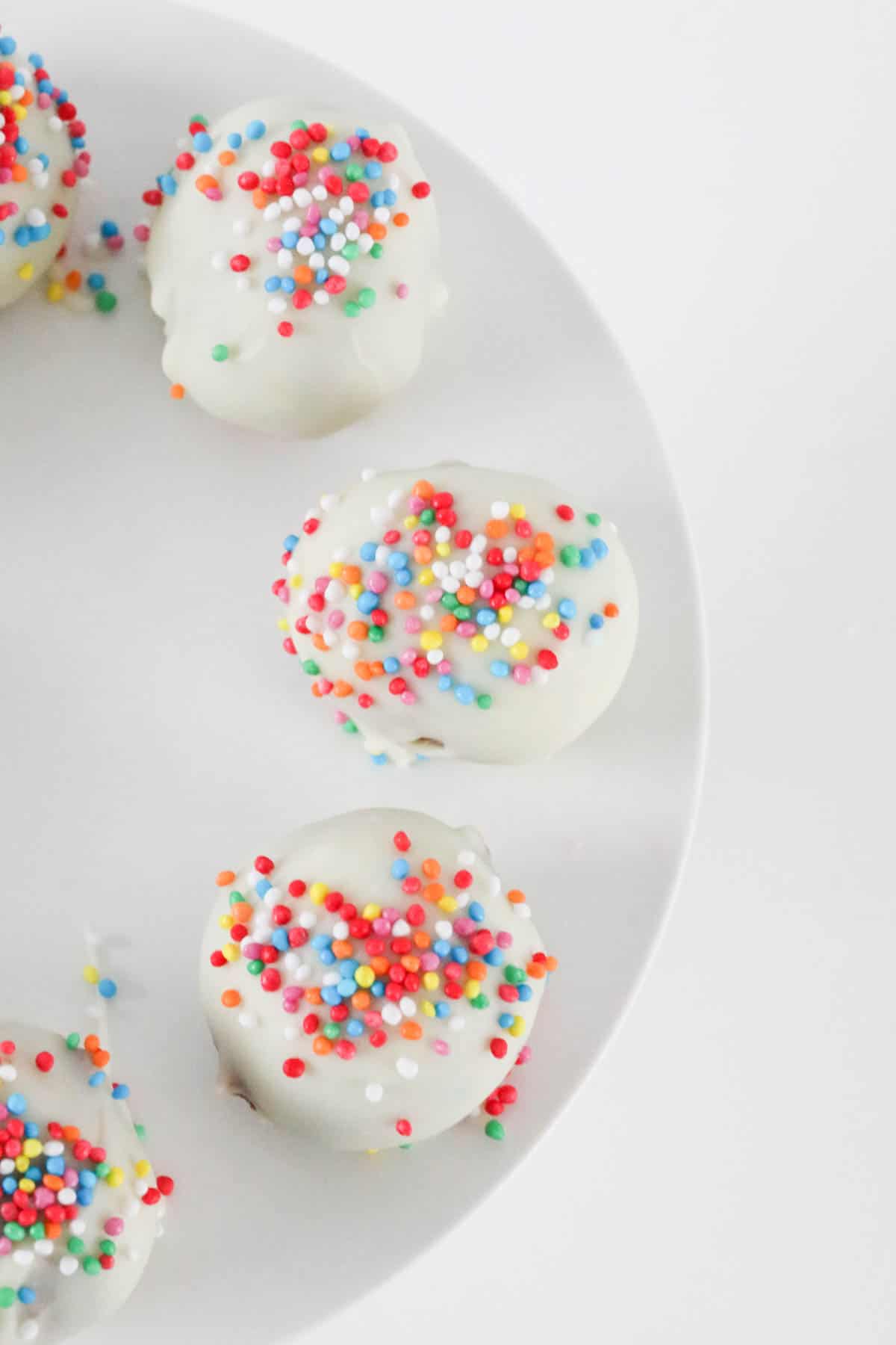 An overhead shot of white chocolate truffles with sprinkles.