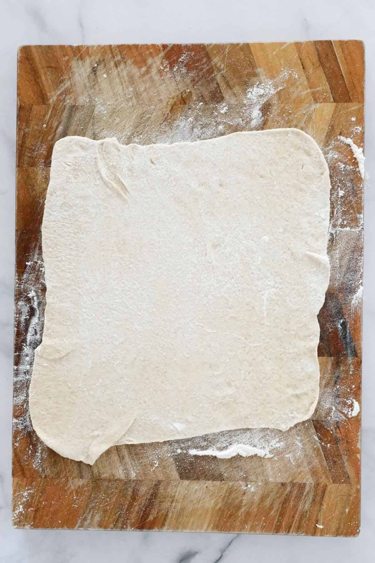 Gozleme dough rolled out thinly on a board.