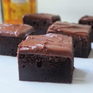 Side view of Kahlua Brownies on a white plate. There is a bottle of Kahlua in the background.