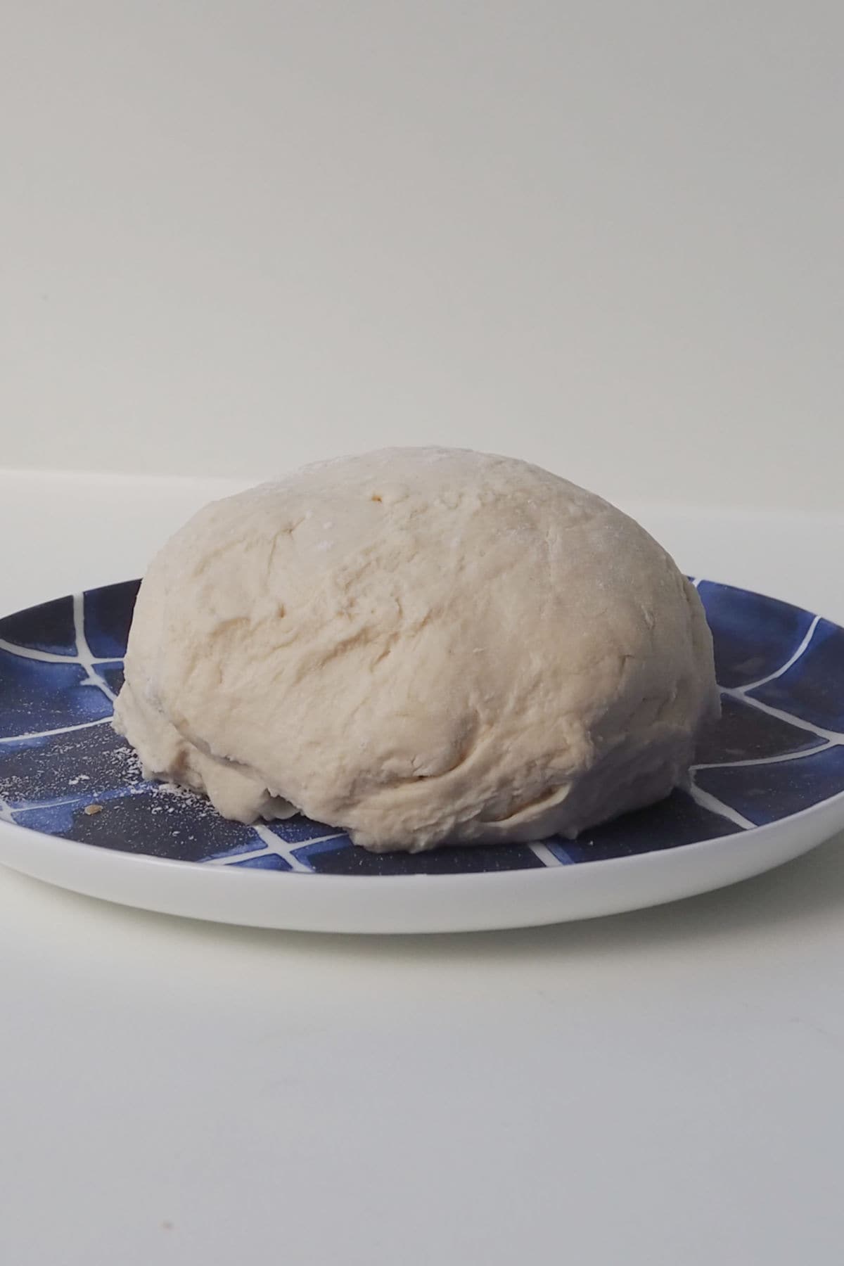Side view of 2 ingredient dough sitting on a blue striped plate.