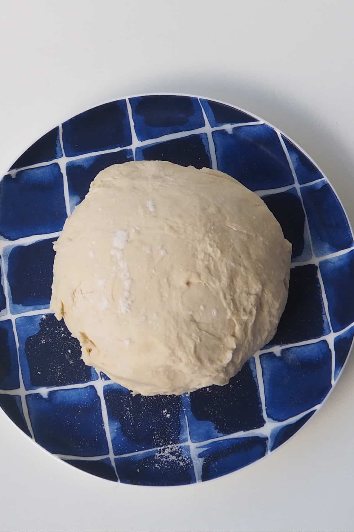 Overhead view of Side view of 2 ingredient dough sitting on a blue striped plate.