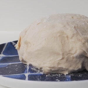 Side view of 2 ingredient dough sitting on a blue striped plate.