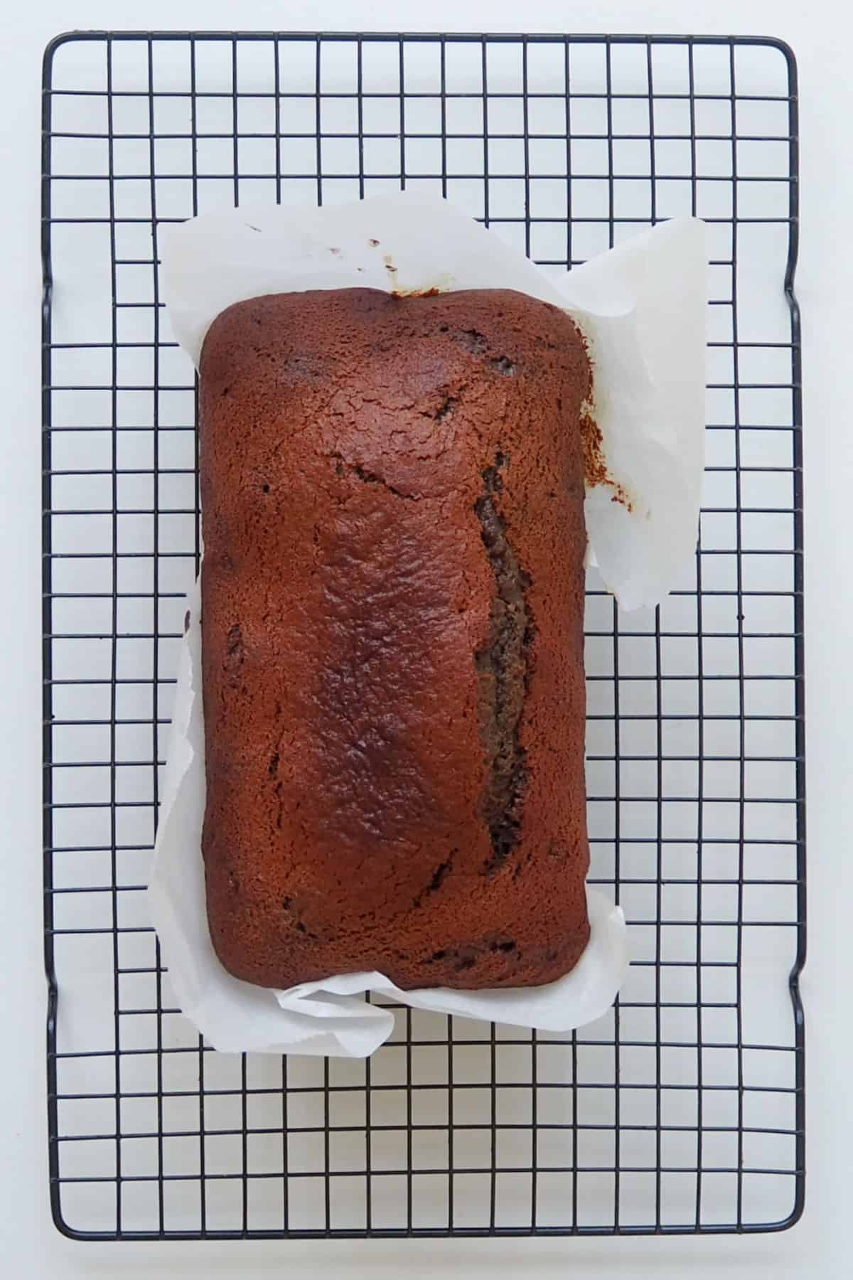 Overhead view of a date loaf straight from the oven sitting on a cooling rack.