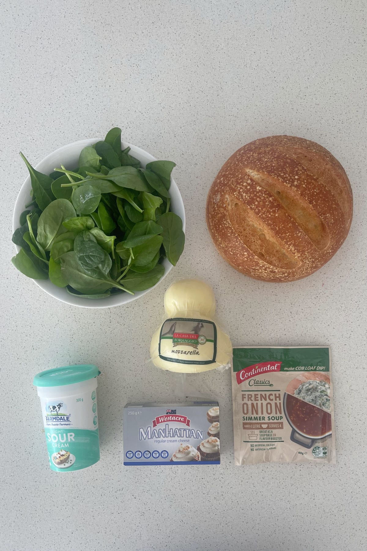 Ingredients to make spinach cob loaf dip on a bench.