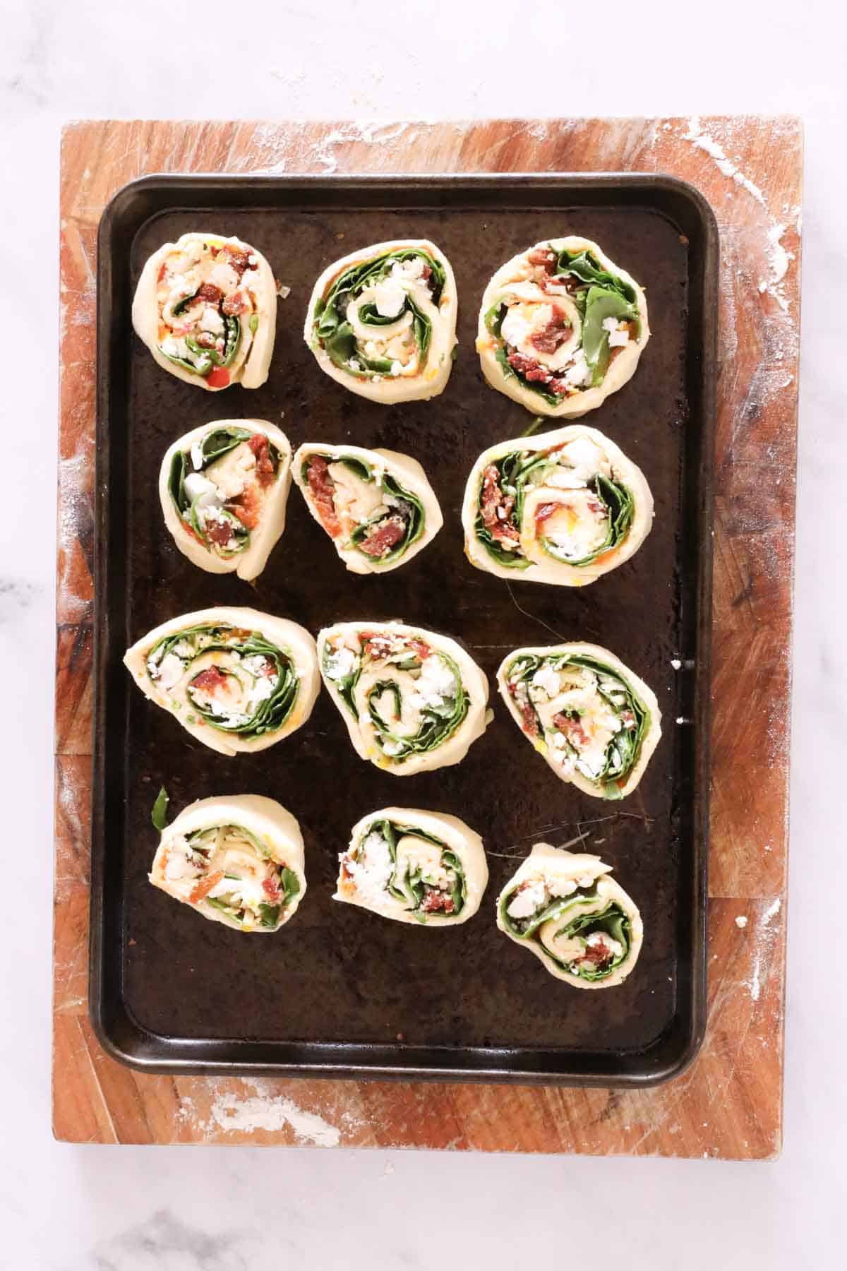 Savoury pinwheel scrolls on a baking tray.