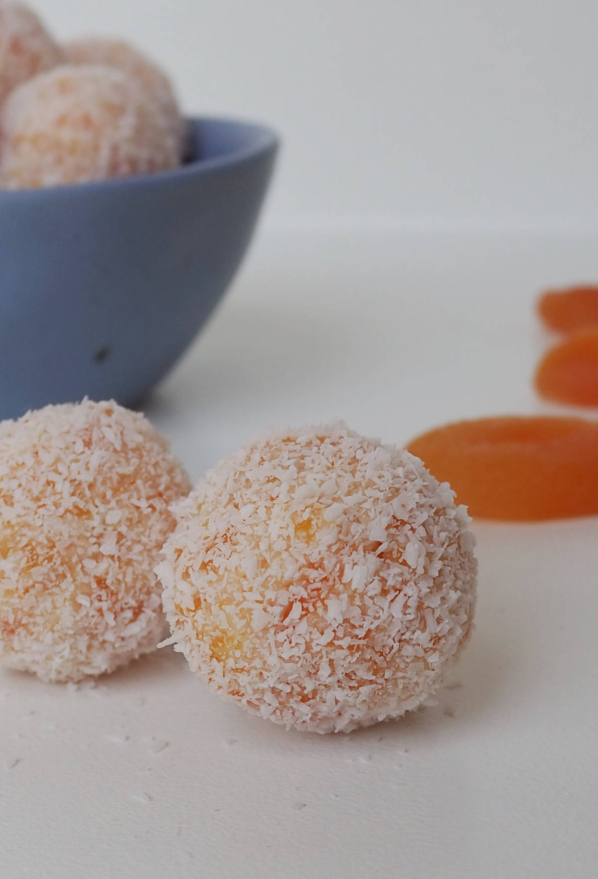 Close up of two apricot balls, behind them is more Apricot Balls sitting in a blue dish.