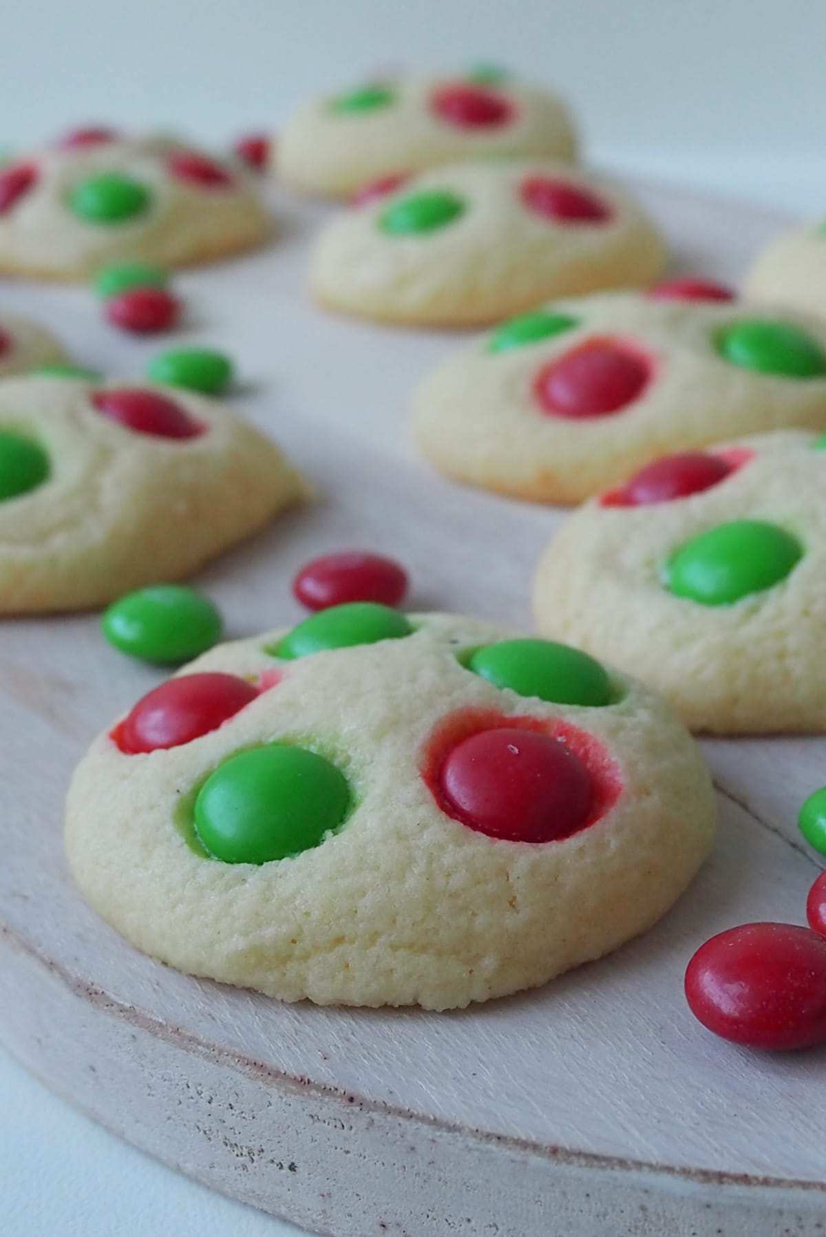Side view of Christmas Biscuits decorated with M&M's on a wooden serving plate.