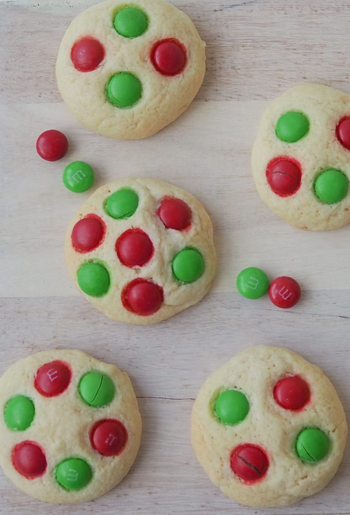 Overhead view of Christmas Biscuits decorated with M&M's on a wooden serving plate.