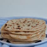 Stack of 10 tortillas sitting on a blue and white spotted plate.