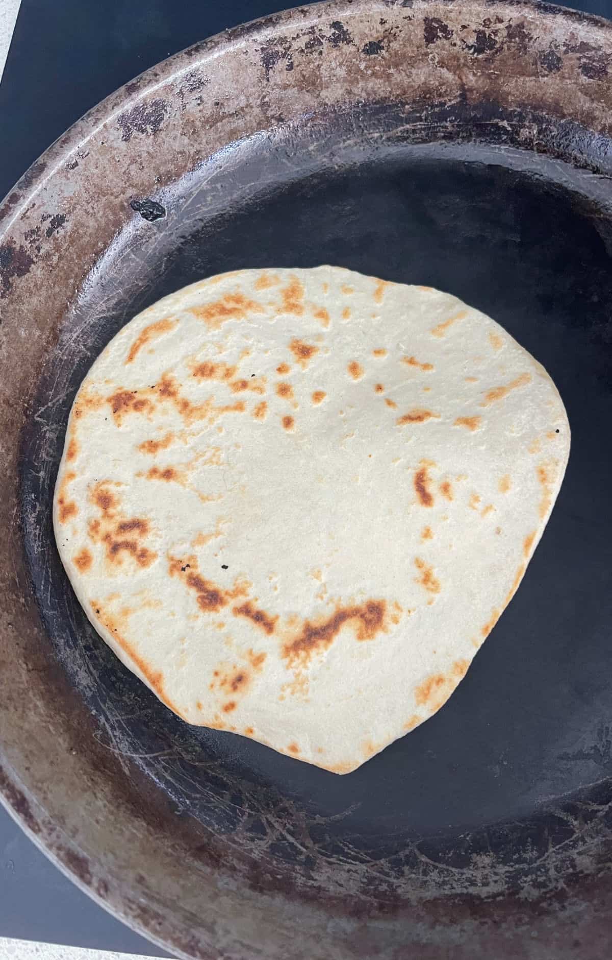 Tortilla cooking in a cast iron frying pan.