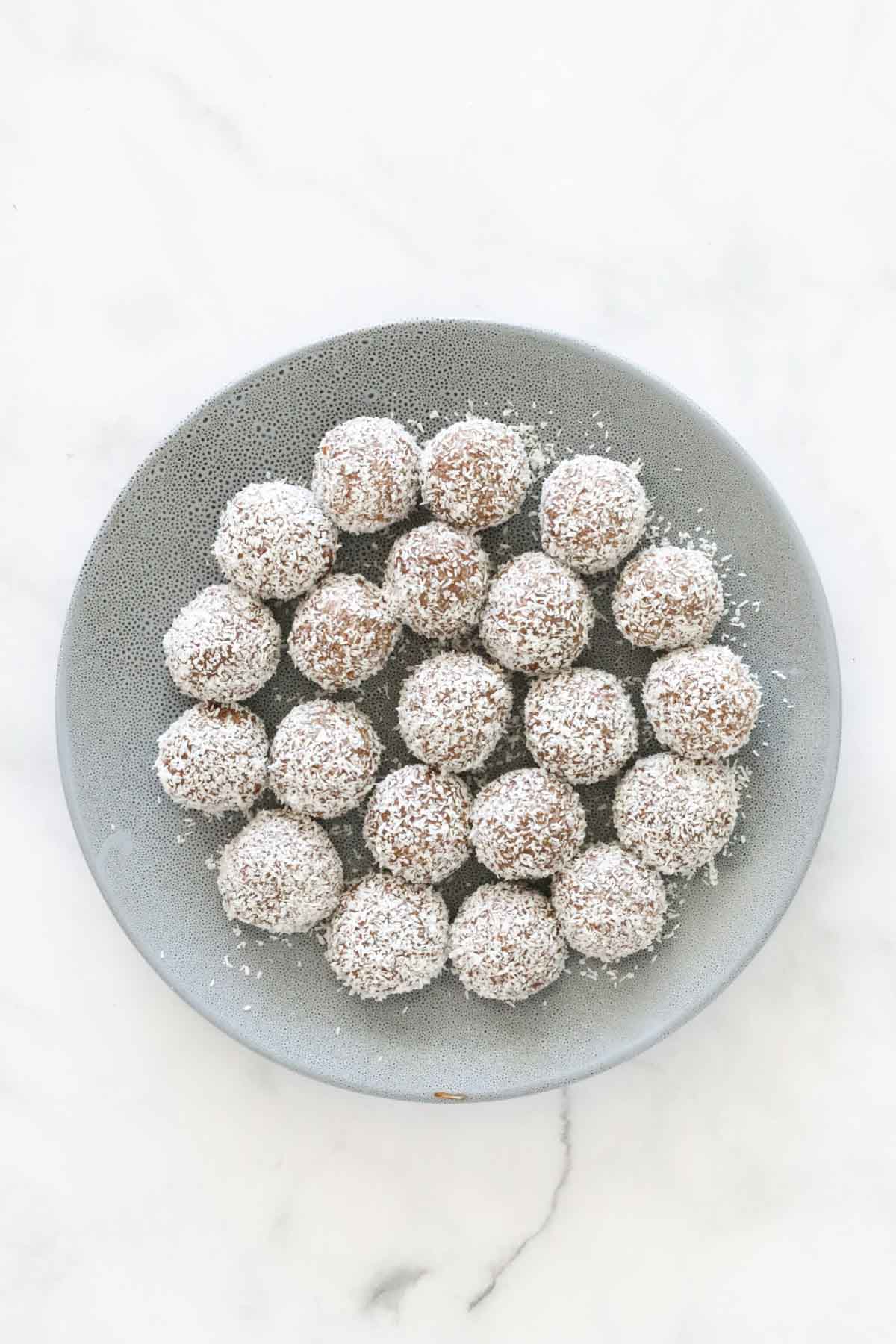 A plate with little coconut coated balls on it.
