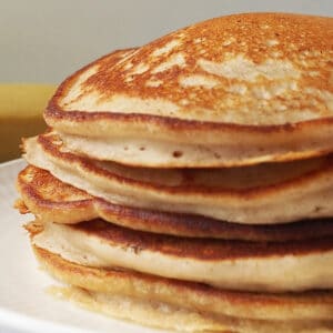 Stack of banana pancakes sitting on a white plate.
