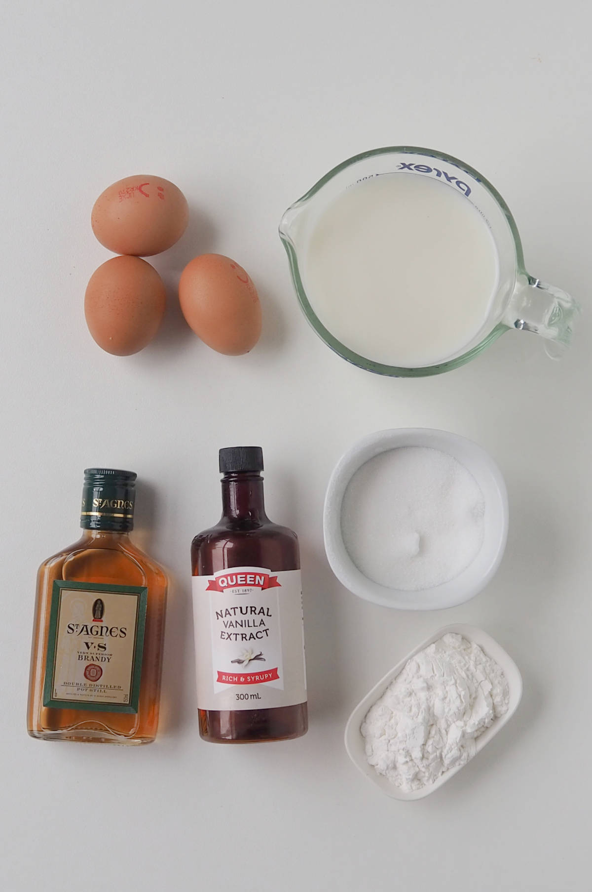 Ingredients to make Brandy Custard on a white bench.