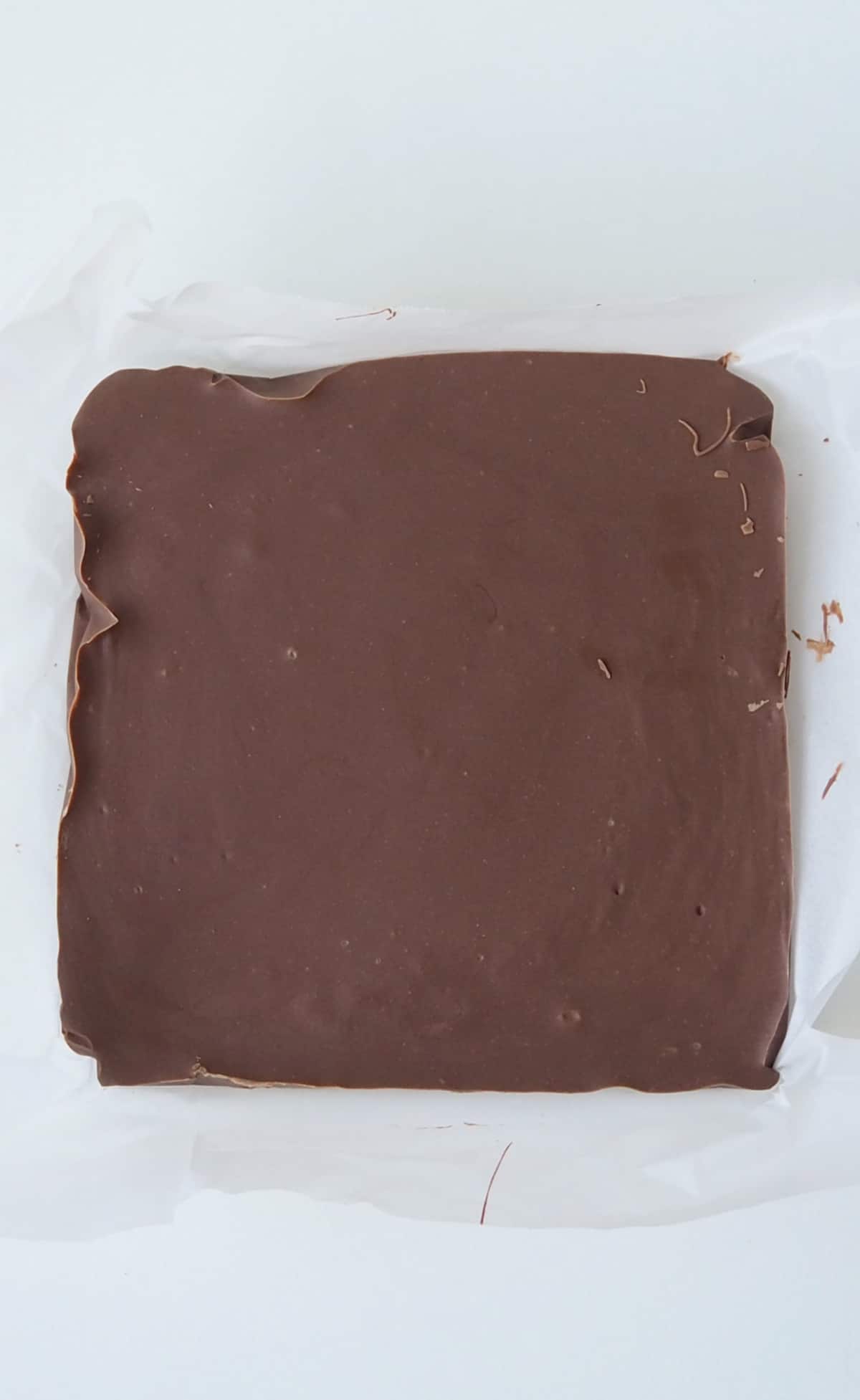 Overhead view of a slab of Baileys Fudge uncut sitting on a piece of baking paper.