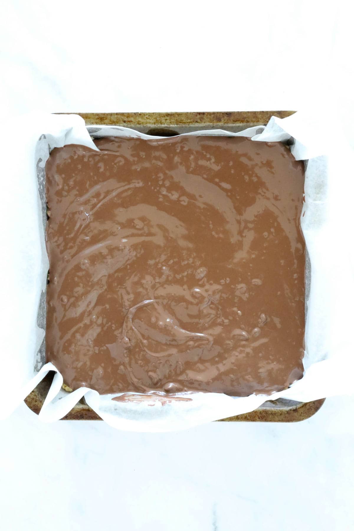 Melted chocolate in a square baking tin.