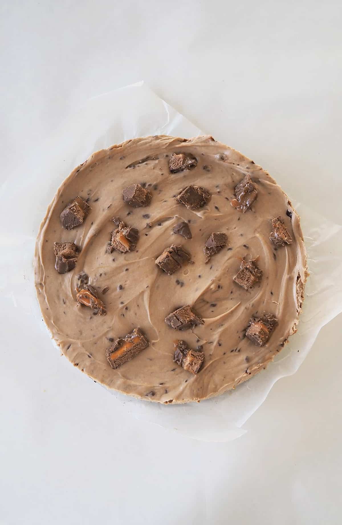 Overhead view of a Mars Bar Cheesecake sitting on a sheet of baking paper.