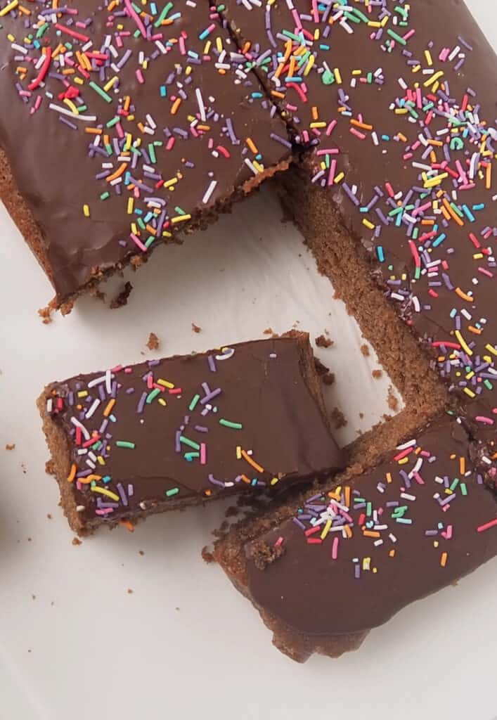 Overhead shot of slices of chocolate cake Topped with a chocolate icing and sprinkles.