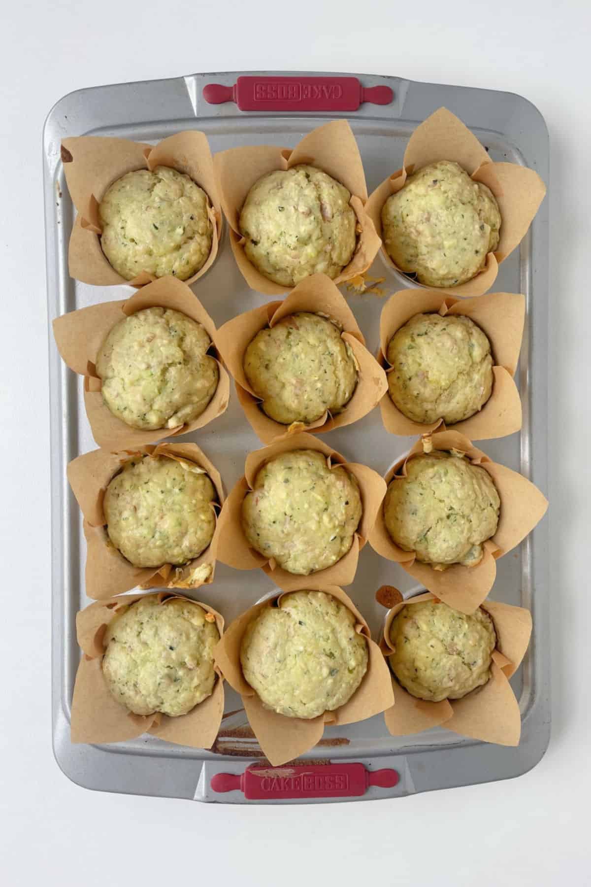 Overhead view of baked savoury muffins straight from the oven in a silver muffin tray.