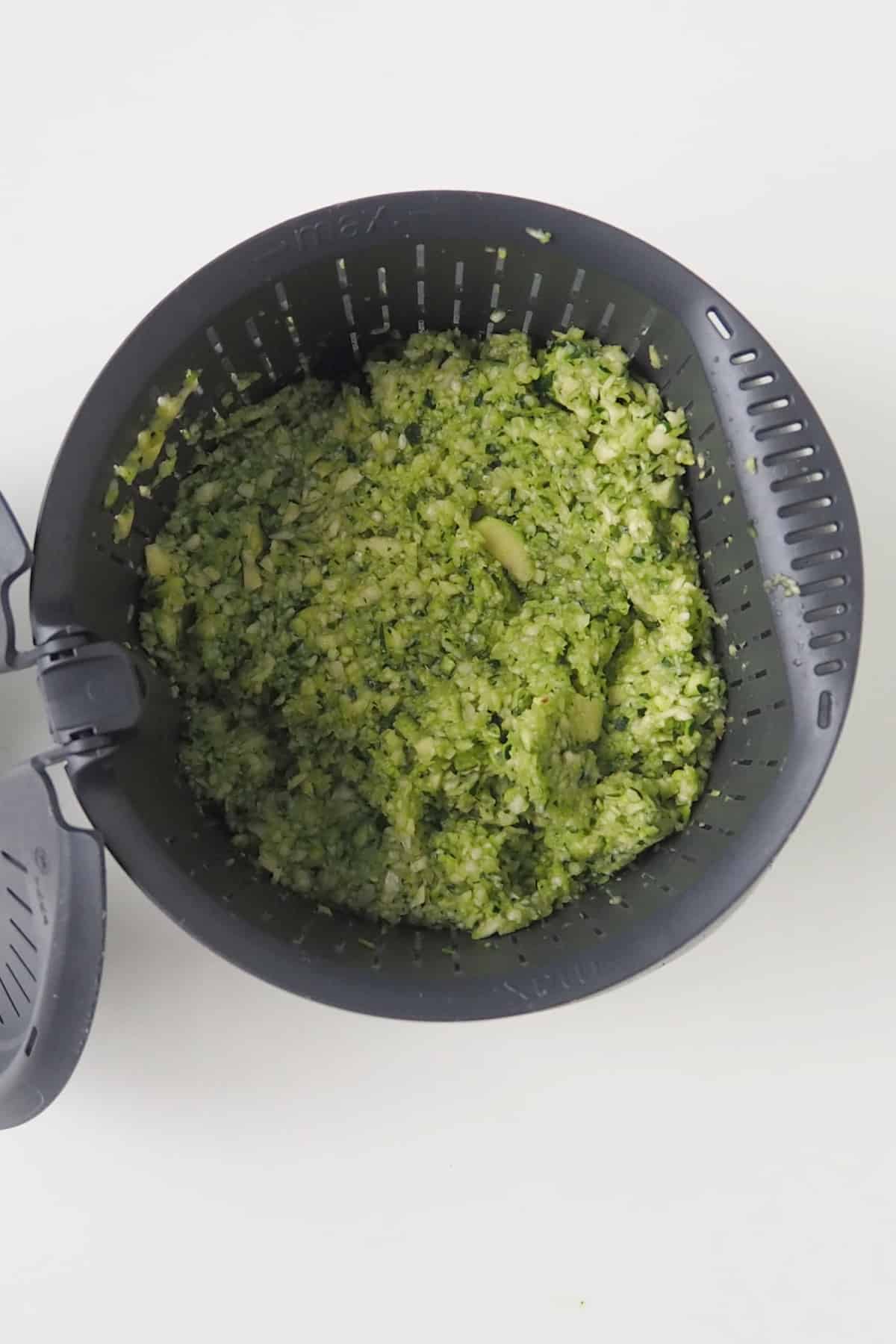 Grated zucchini draining in a thermomix basket.