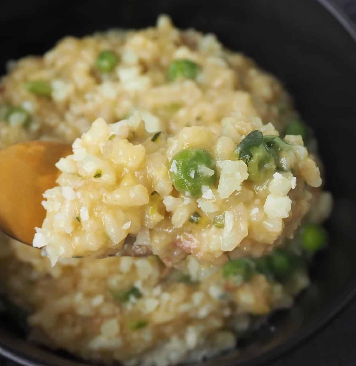 gold fork holding up Bowl of Thermomix Zucchini Pea and Bacon risotto.