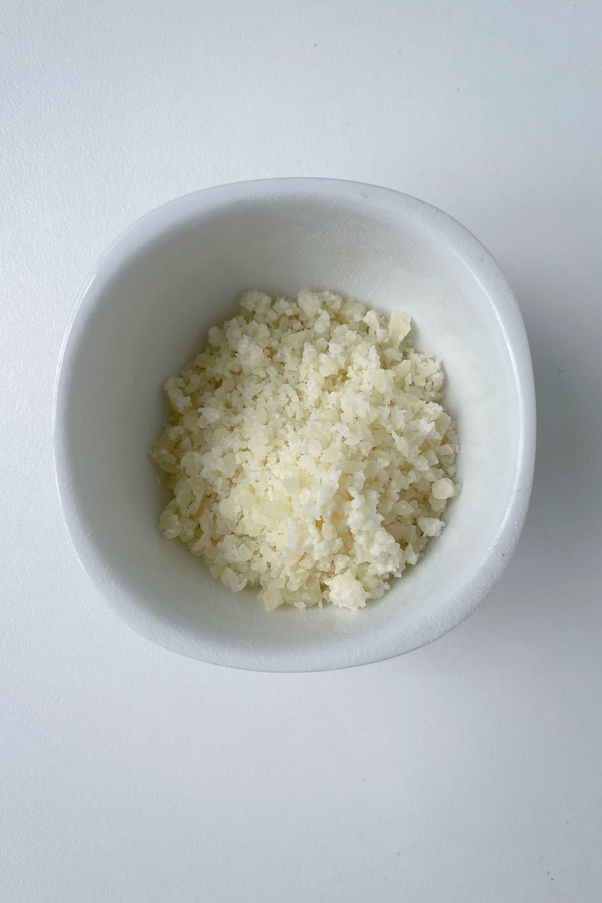 Grated cheese in a white bowl.