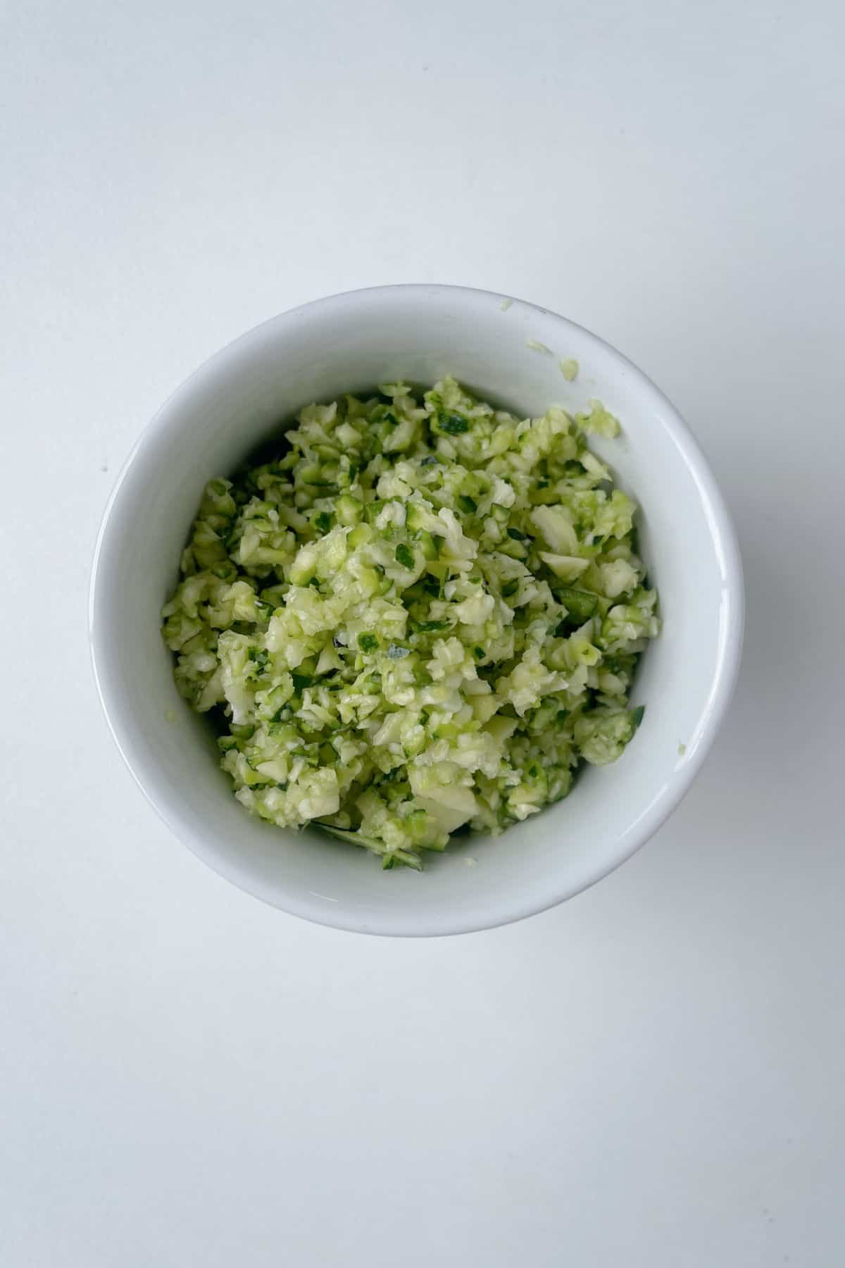 Grated zucchini in a white bowl.