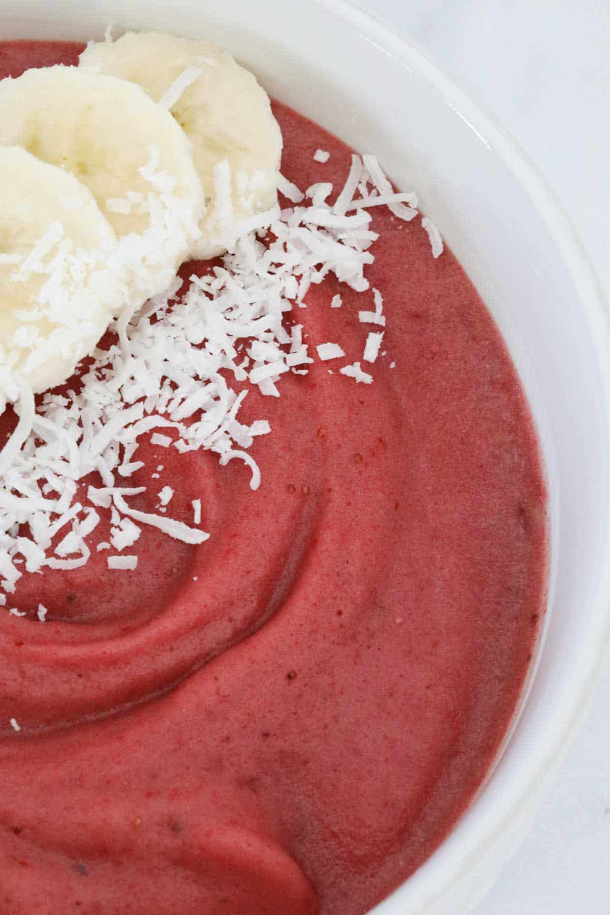 Coconut and banana on a berry smoothie bowl.