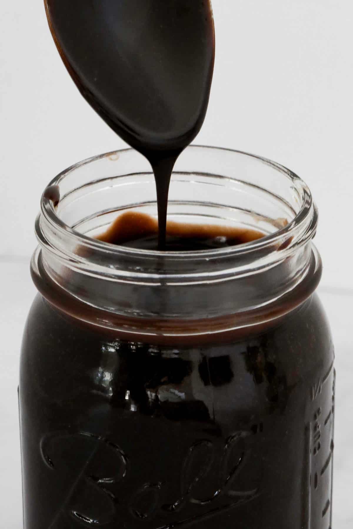 A spoon with chocolate sauce dripping down.