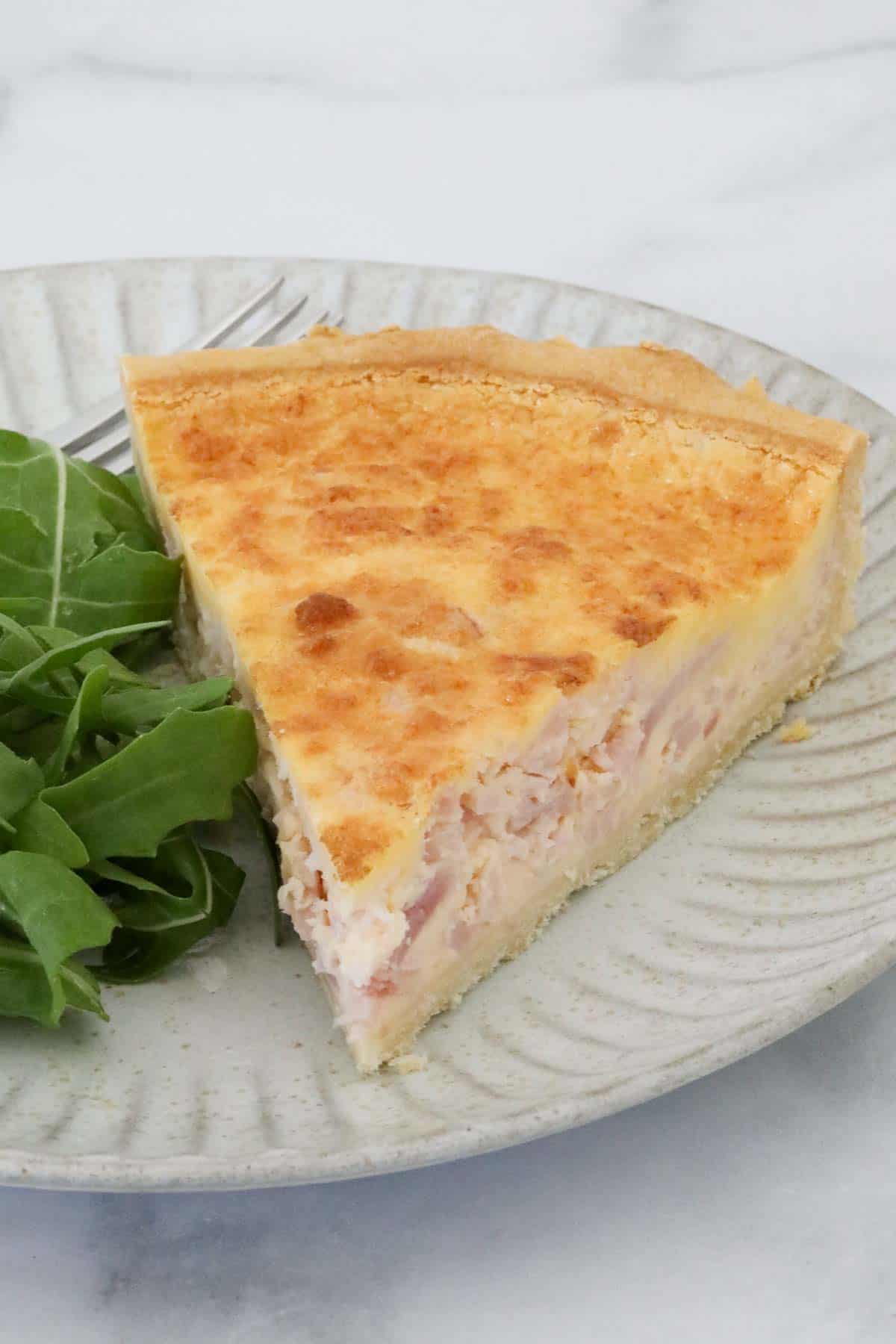 A piece of quiche on a plate. 