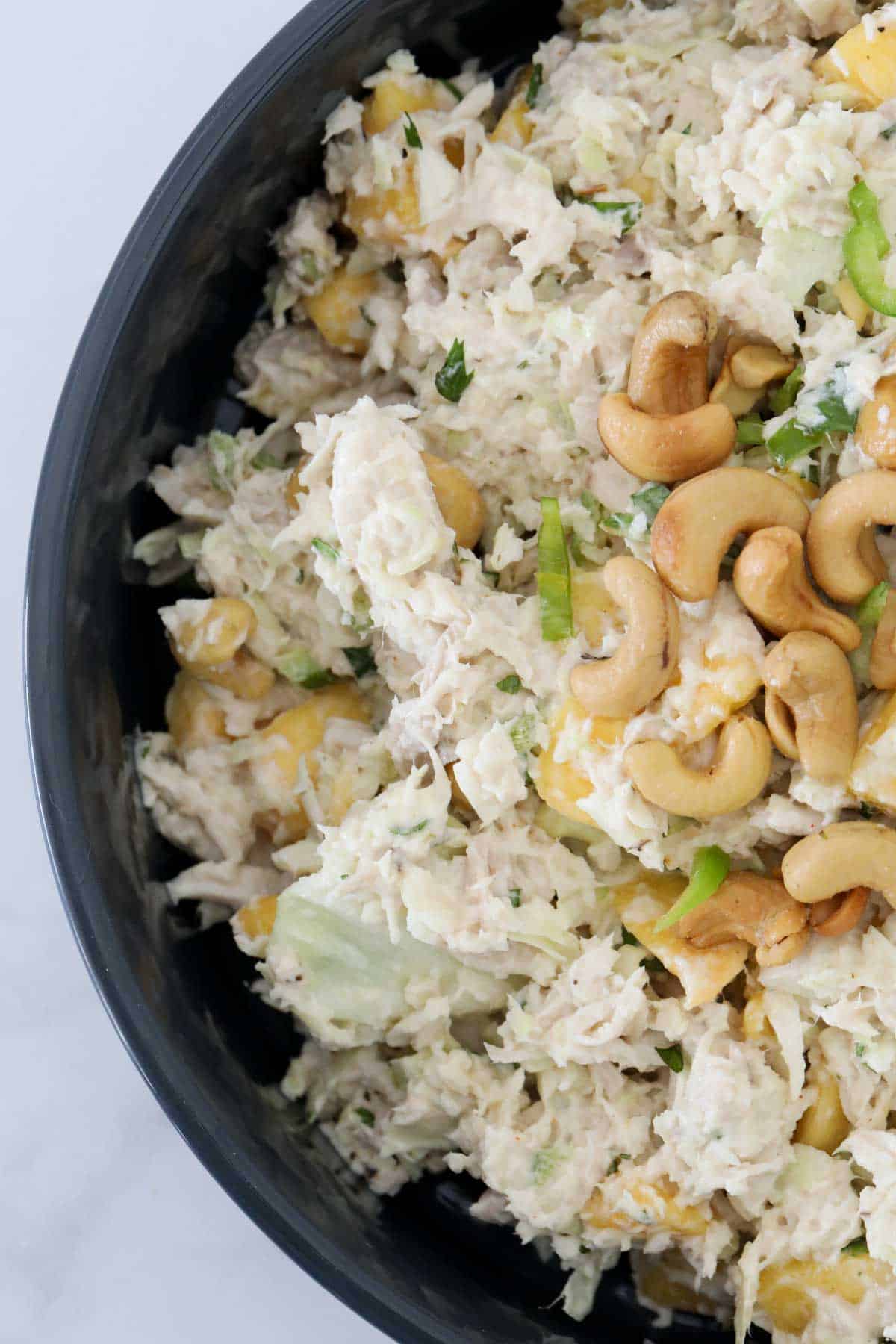 An overhead shot of a salad bowl topped with cashews.