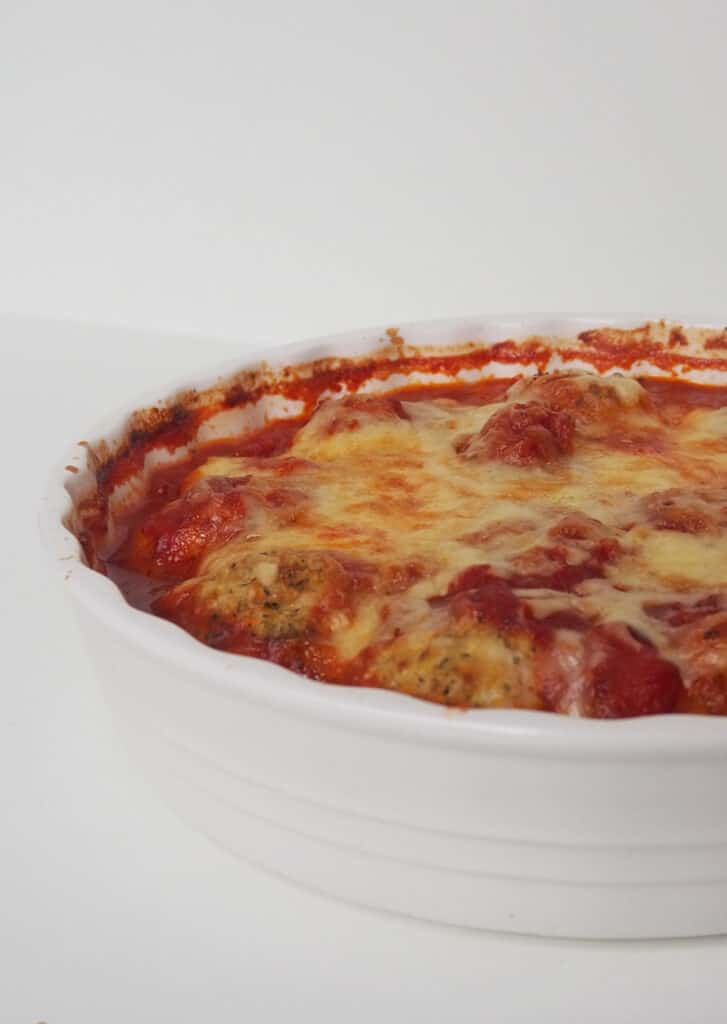 Side view of Chicken Parma Balls in a white baking dish straight from the oven.