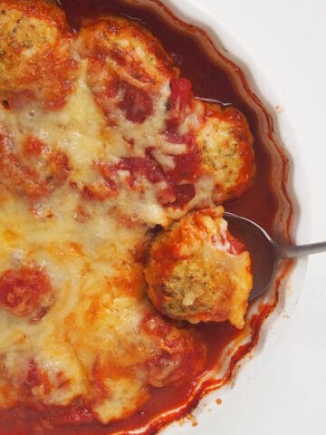Overhead view of a large spoon scooping up a Chicken Parma Ball.
