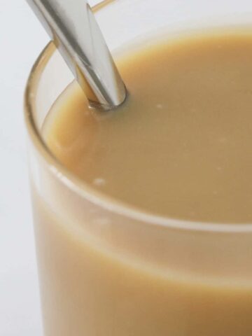 A spoon in a glass jar of caramel sauce.