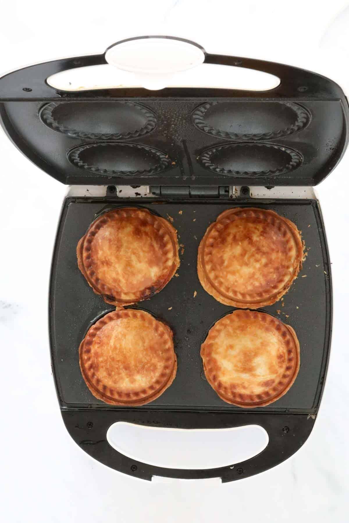 4 cooked pies in a pie maker.