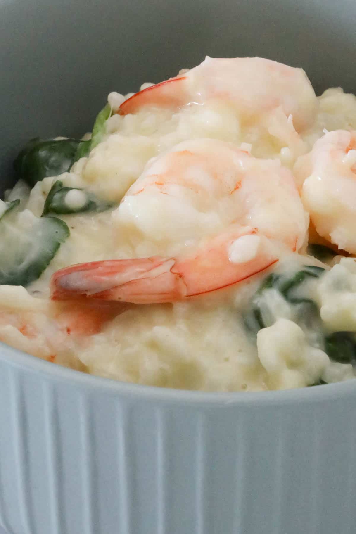A bowl of risotto with prawns and spinach.