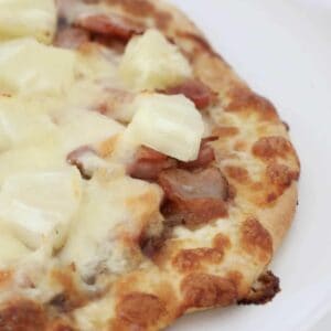 A homemade pizza topped with pineapple, cheese and bacon.