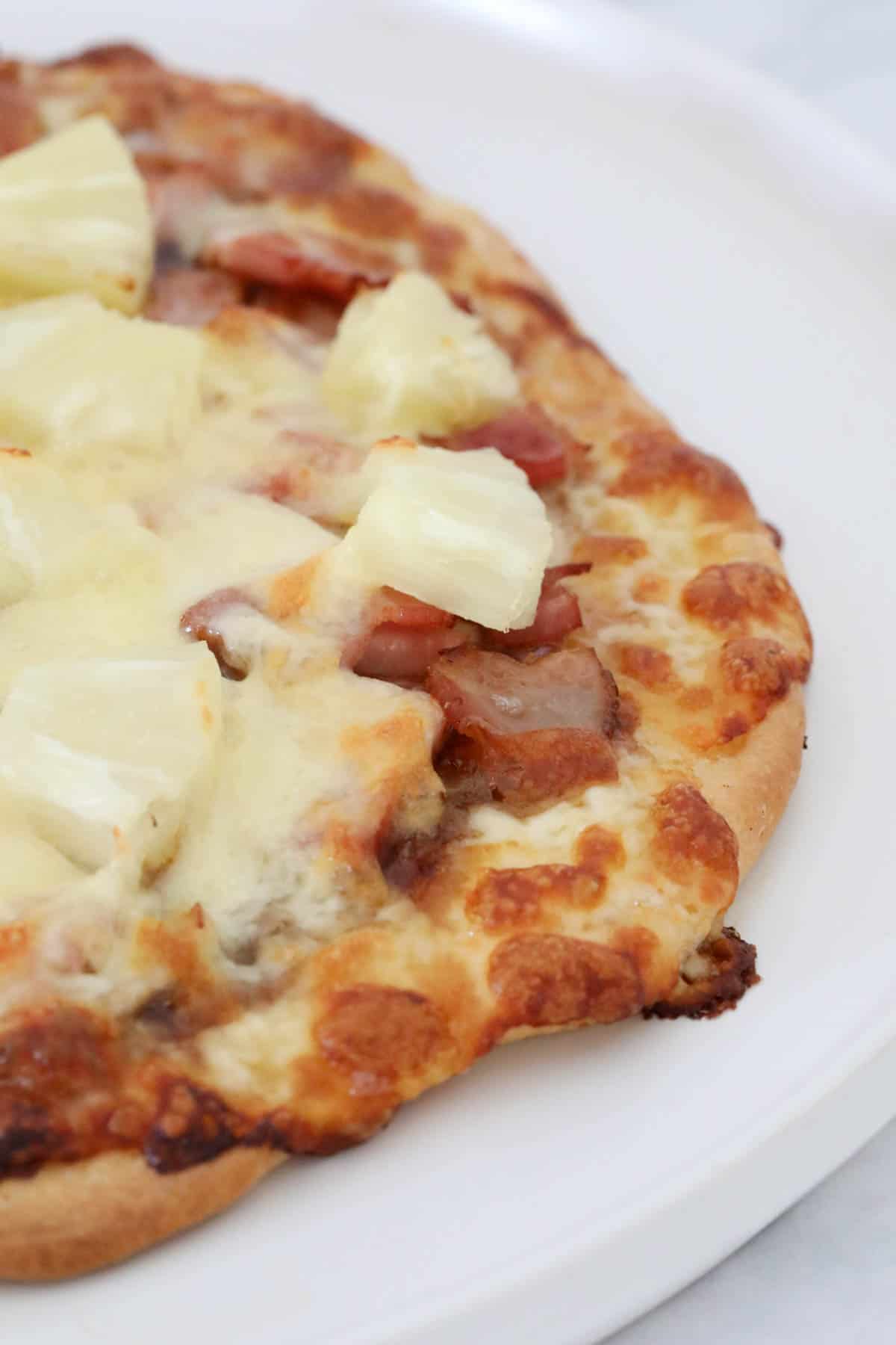 A pizza topped with cheese, bacon and pineapple.