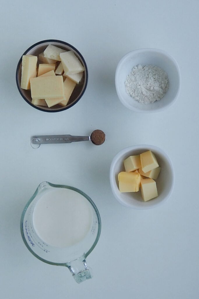 Ingredients to make cheese sauce in a thermomix on a bench top.