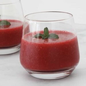 A glass of raspberry drink with mint.