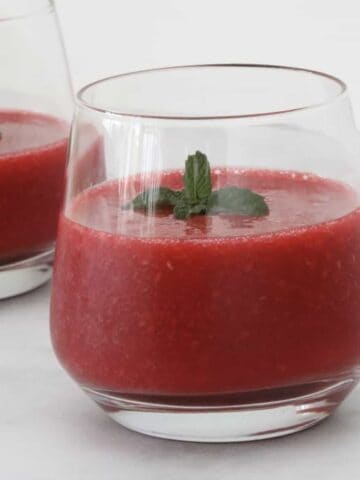 A glass of raspberry drink with mint.