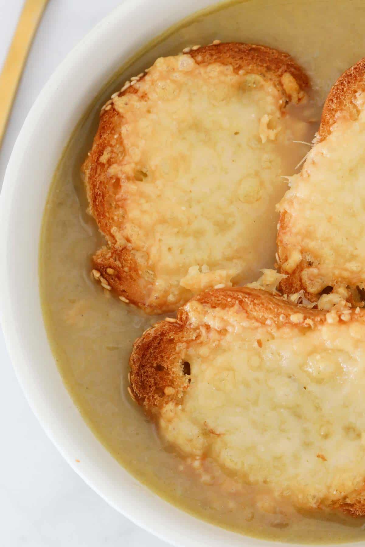 Cheesy baguettes on top of a soup.