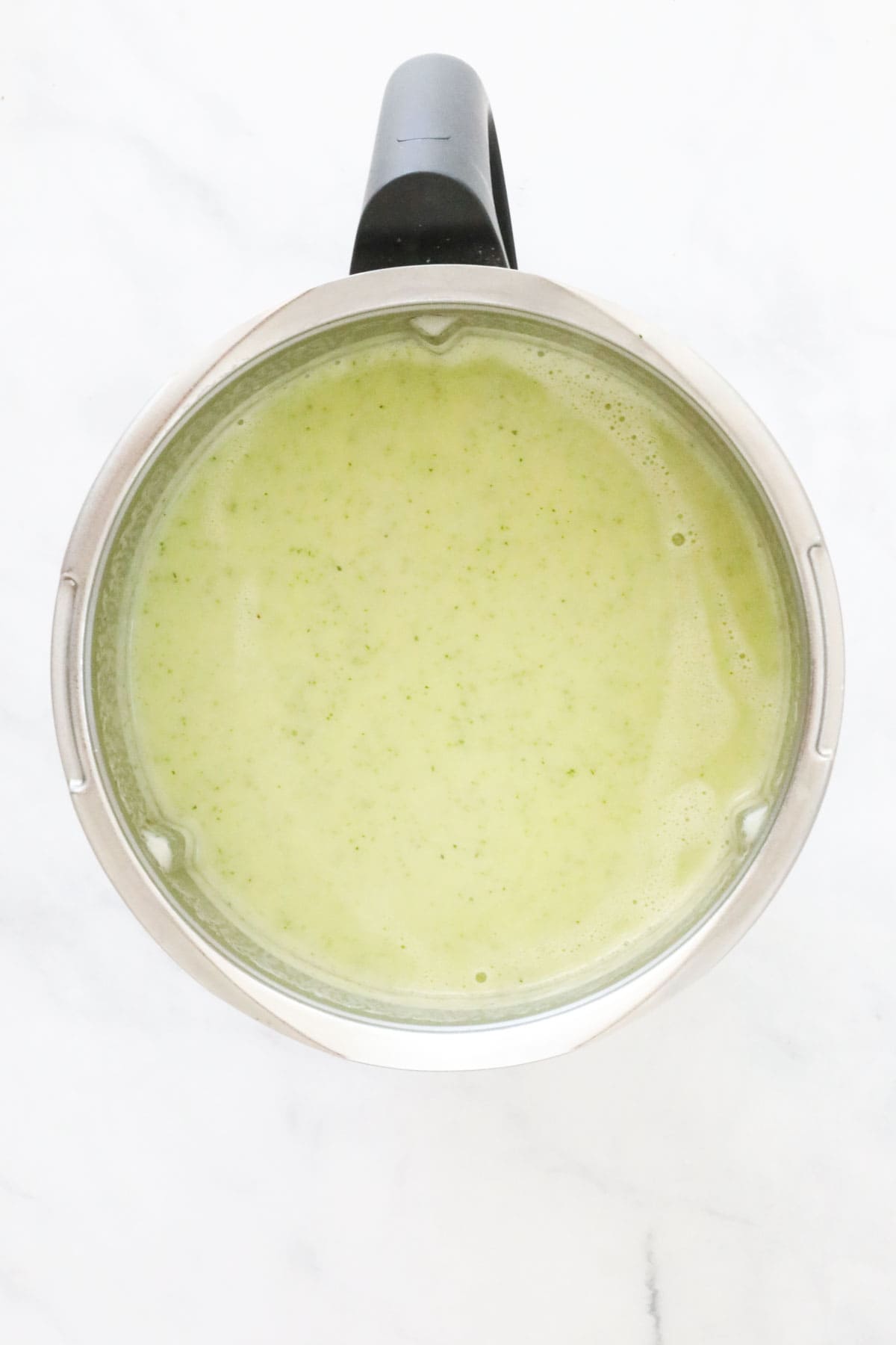 A Thermomix bowl filled with creamy zucchini soup.