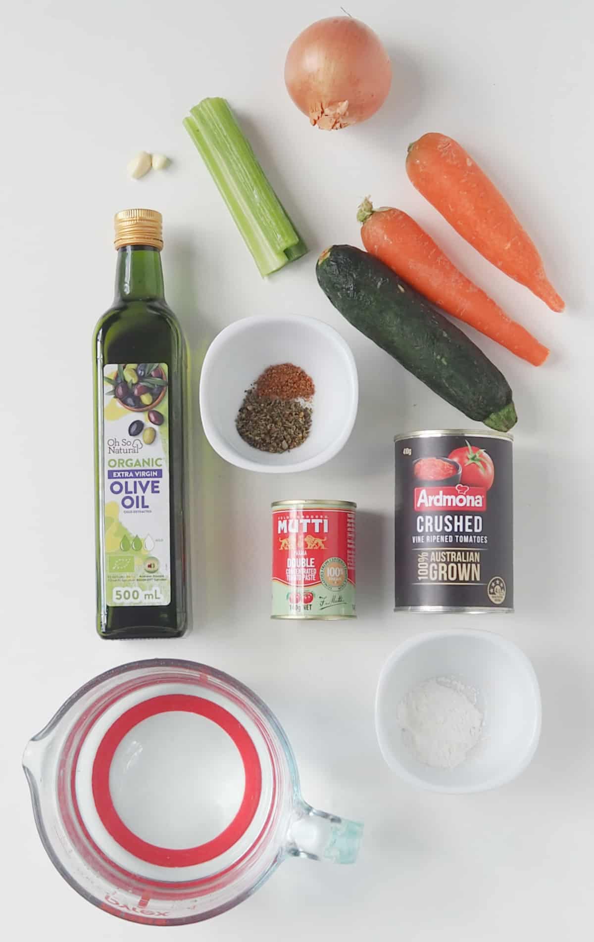 Ingredients to make spicy tomato soup on a white bench top.