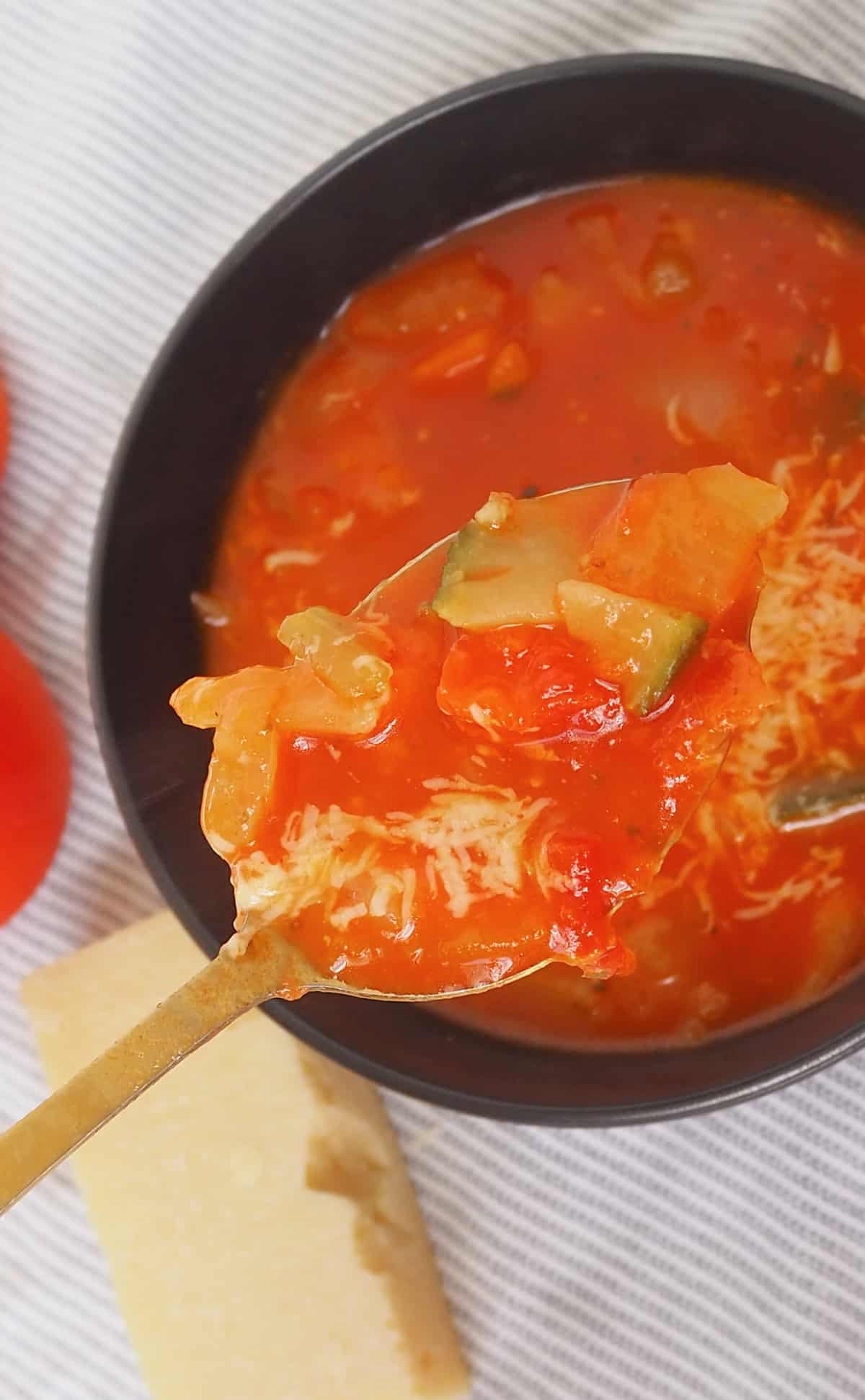 gold spoon holding Thermomix Spicy Tomato Soup.