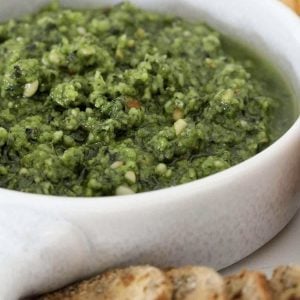 A bowl filled with green nutty pesto.