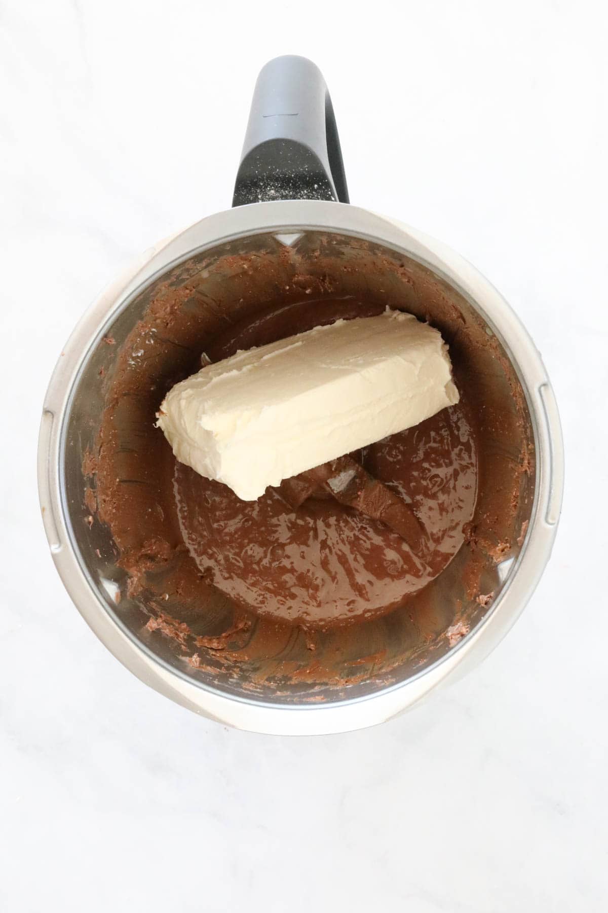 Cream cheese on top of melted chocolate in a Thermomix bowl.