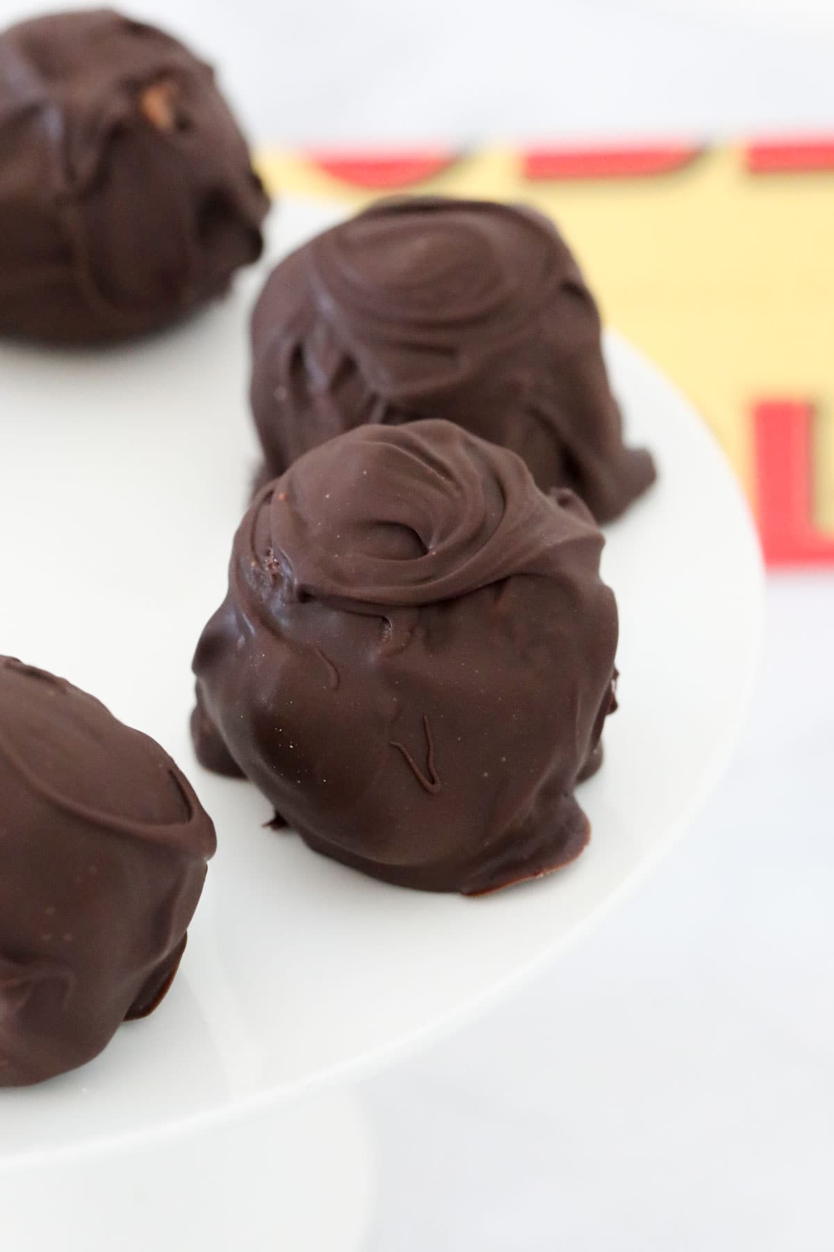 Chocolate coated balls on a white cake stand.