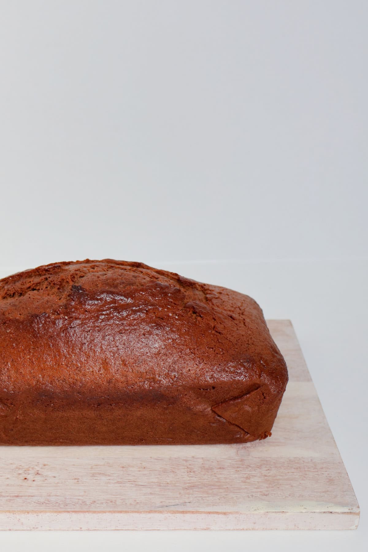 Side view of gingerbread loaf on a timber board before being cut.