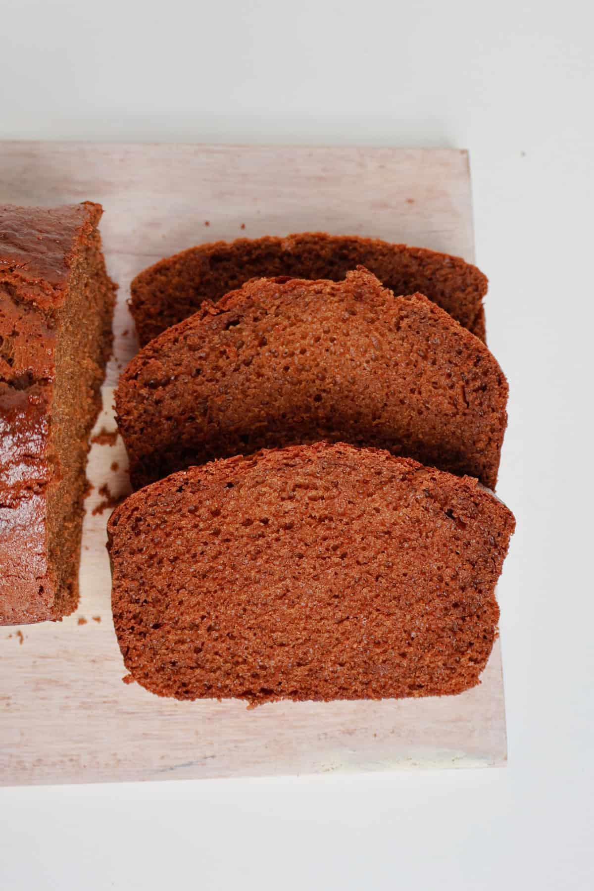 Three pieces of Gingerbread loaf sliced on a timber board.