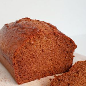 Gingerbread loaf sliced in half and sitting on a timber board.